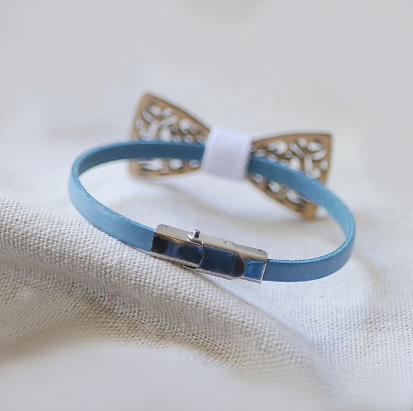 Bracelet en cuir bleu avec nœud papillon en bois ajouré.
